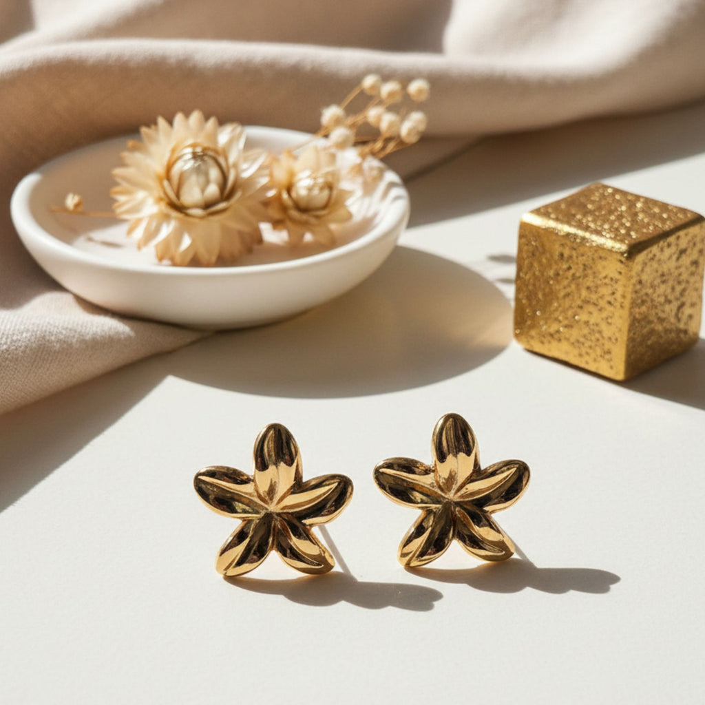 Gold floral stainless steel stud earrings on ceramic dish – high-polish five-petal design for women